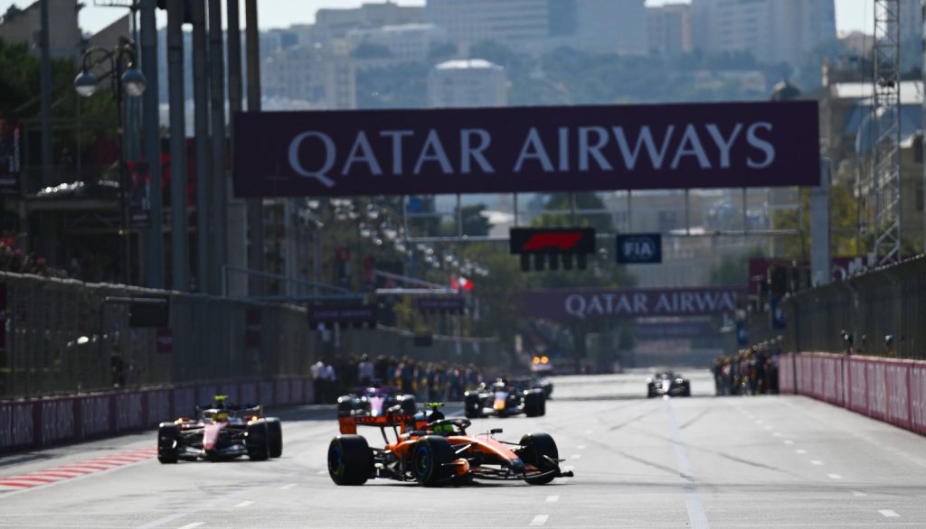 Papaya-colored McLaren leads several Formula 1 cars beneath the Qatar Airways gantry on Baku’s main straight.