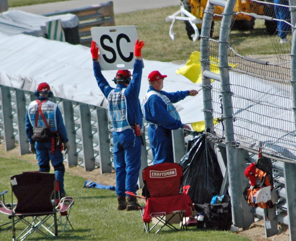 A marshal waves a yellow flag beside a safety-car board during the 2005 United States Grand Prix.