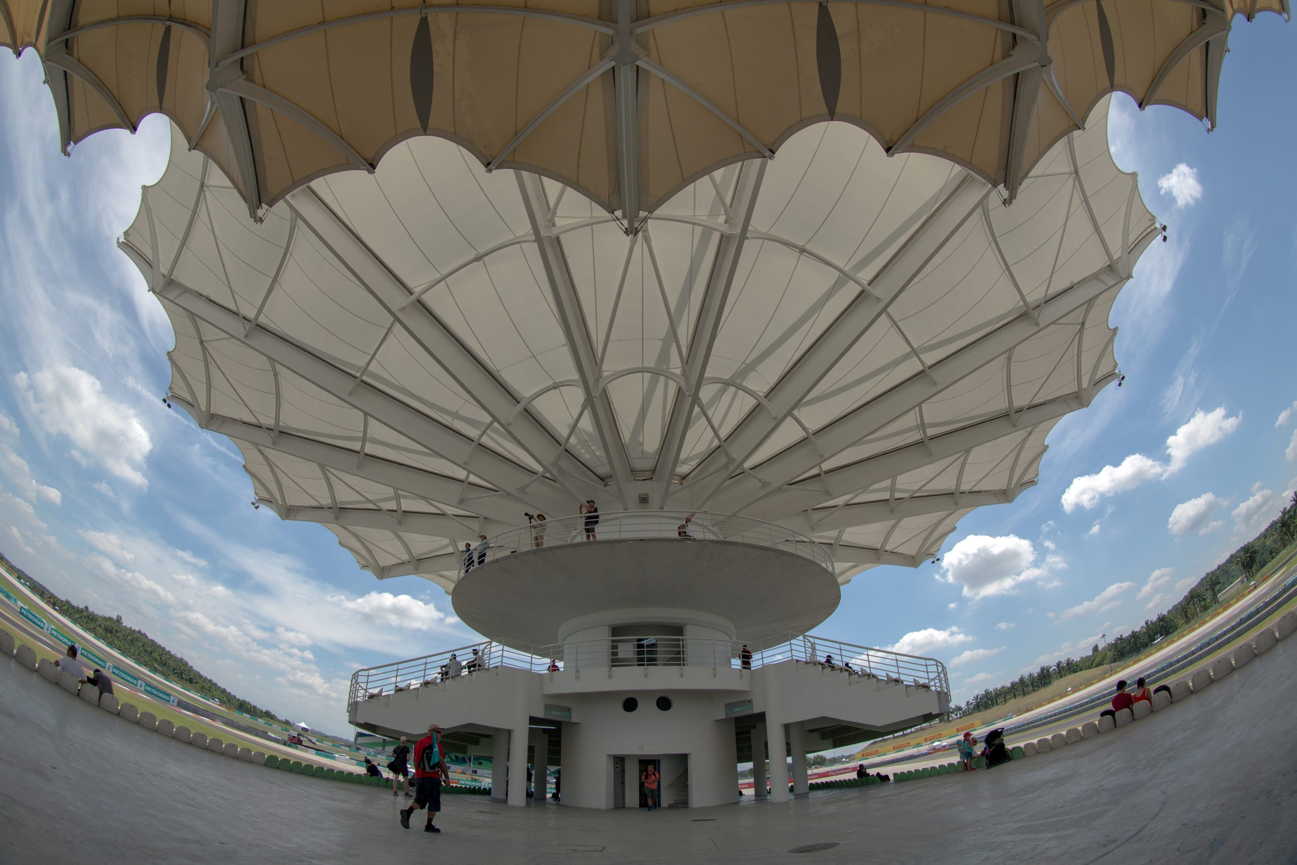 Exterior view of the covered grandstand tower, palm trees, and perimeter roadway at Sepang International Circuit in Malaysia.