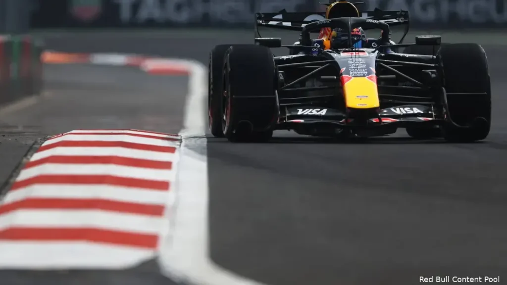 A Red Bull Racing Formula One car driving on a racetrack beside a red and white kerb.