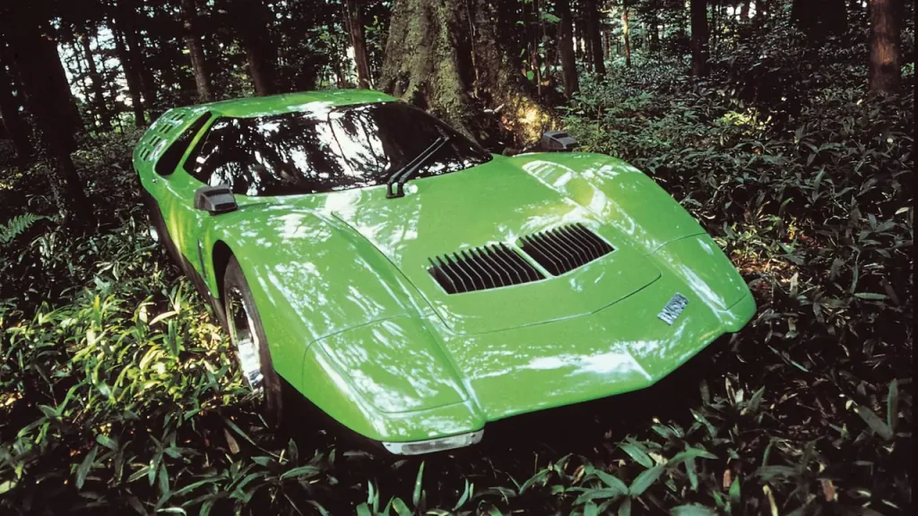 A green Mazda RX-500 concept car parked among foliage in a wooded area.
