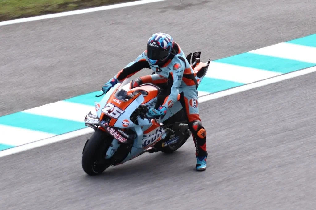 A motorcycle racer rides along a paved circuit next to the track kerbing.