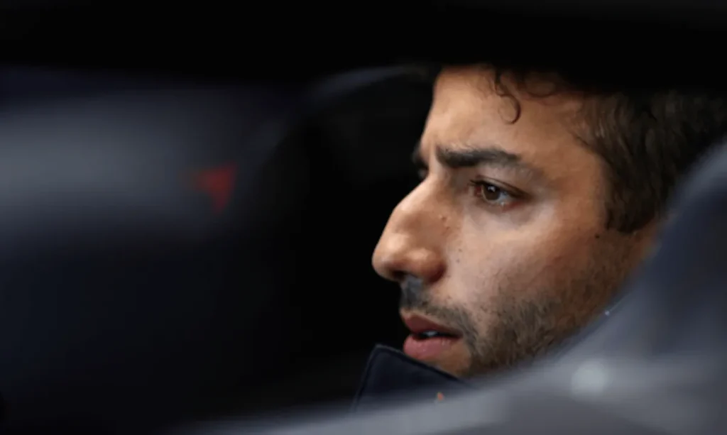 Close-up profile of Daniel Ricciardo looking out from inside a racing car cockpit.