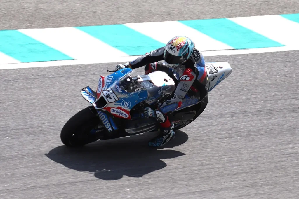 A motorcycle racer leans into a turn on a paved racing circuit beside a painted kerb.