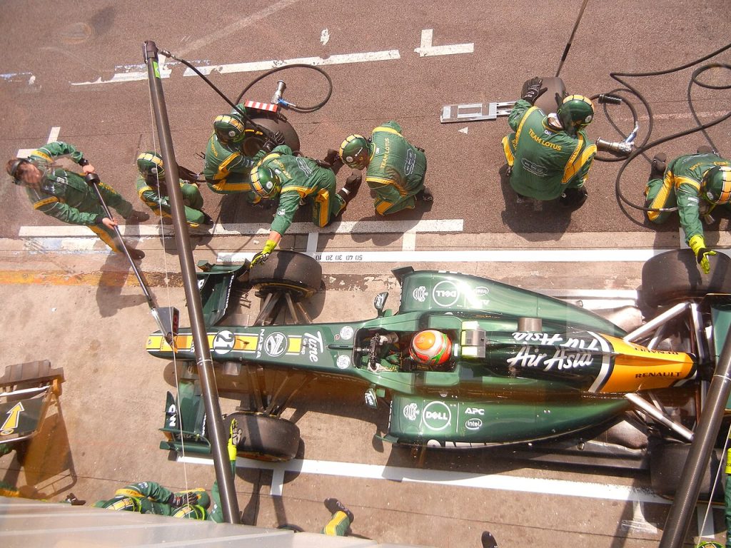 A Team Lotus Formula 1 car in the pit lane during a Grand Prix race weekend.