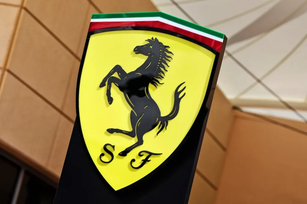 A yellow Ferrari shield emblem featuring a black prancing horse with Italian tricolor stripes at the top and the letters S F below.