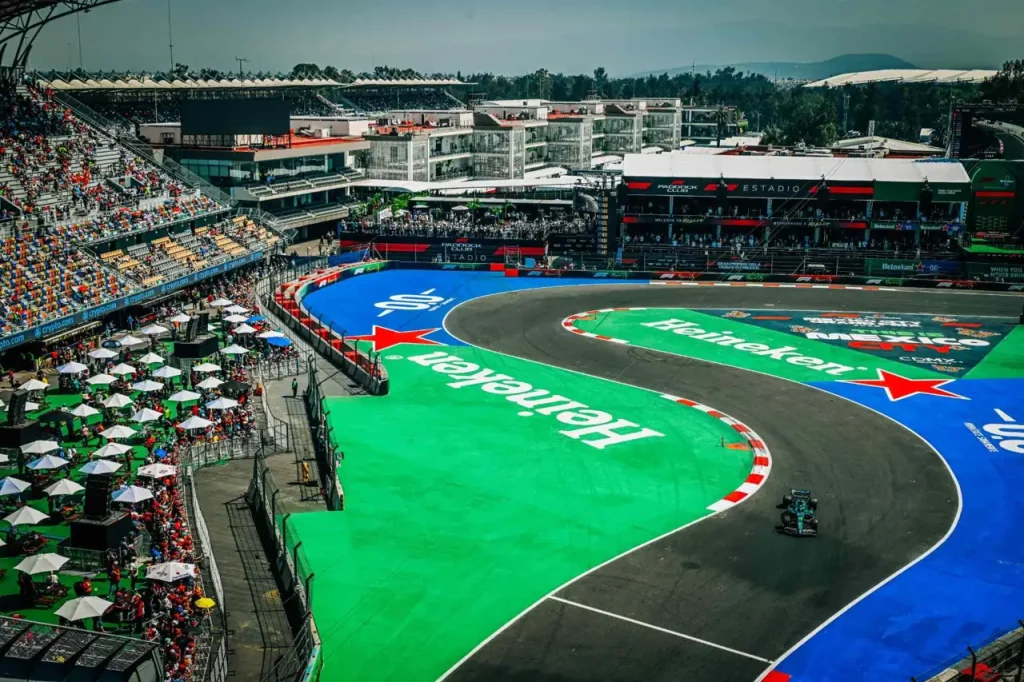 Aerial view of a Formula 1 car navigating a curved section of a racetrack bordered by grandstands filled with spectators.