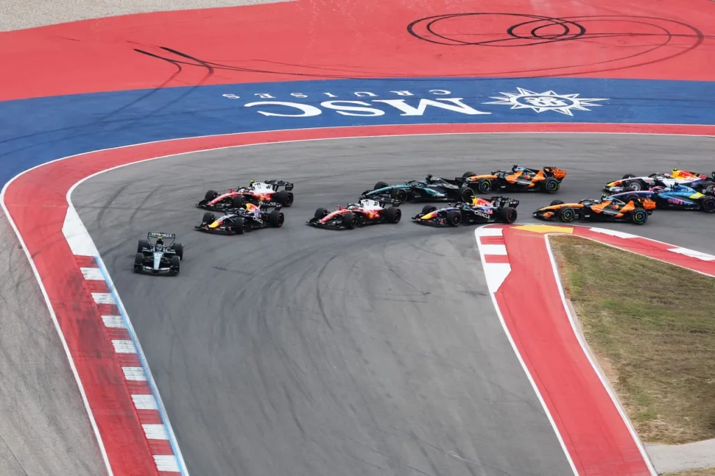 Formula 1 cars rounding a corner on a circuit with painted run-off areas.