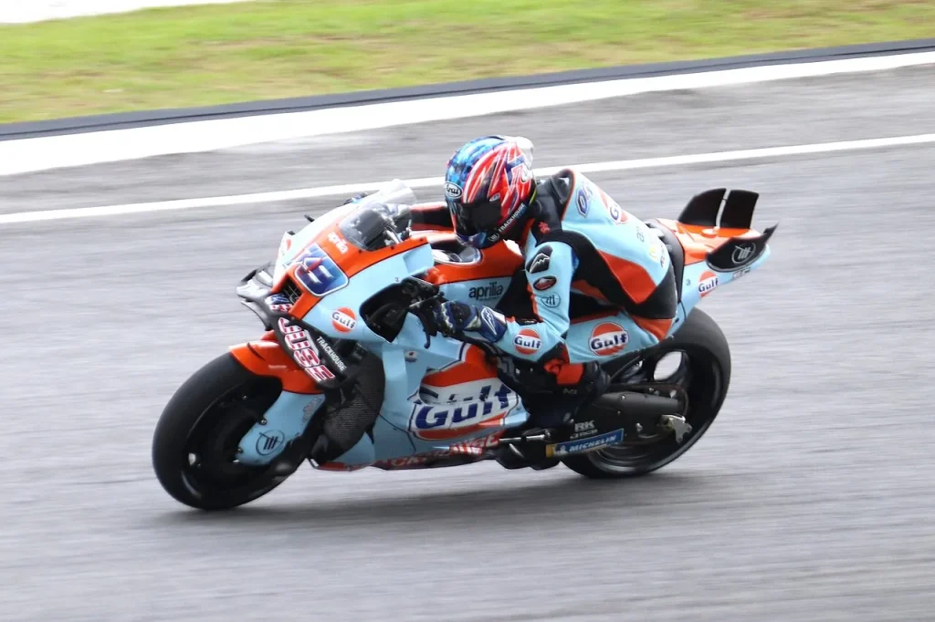 A Grand Prix motorcycle rider leans through a turn on a racetrack.