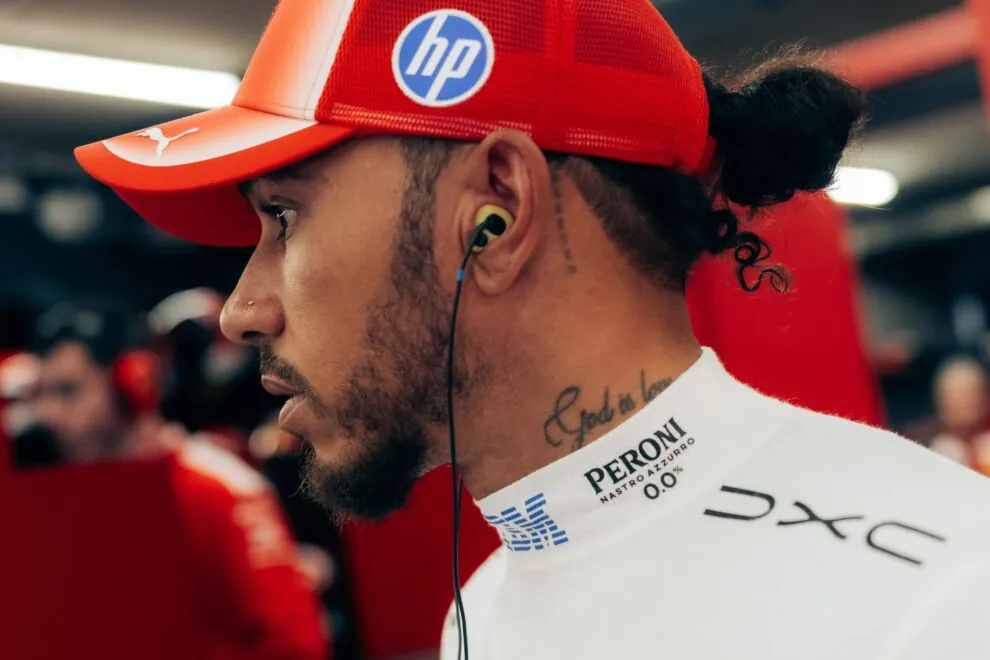 Profile of a man wearing a red cap and white high-collar fireproof undershirt with an earphone.