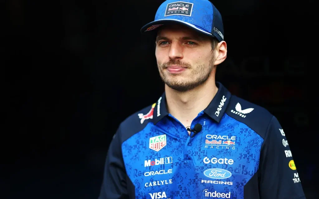 A man wearing a blue Oracle Red Bull Racing cap and team polo shirt against a dark background.