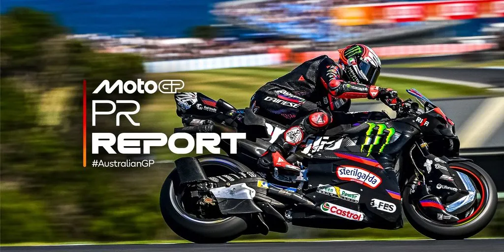 A motorcycle racer leans into a turn on an asphalt circuit.